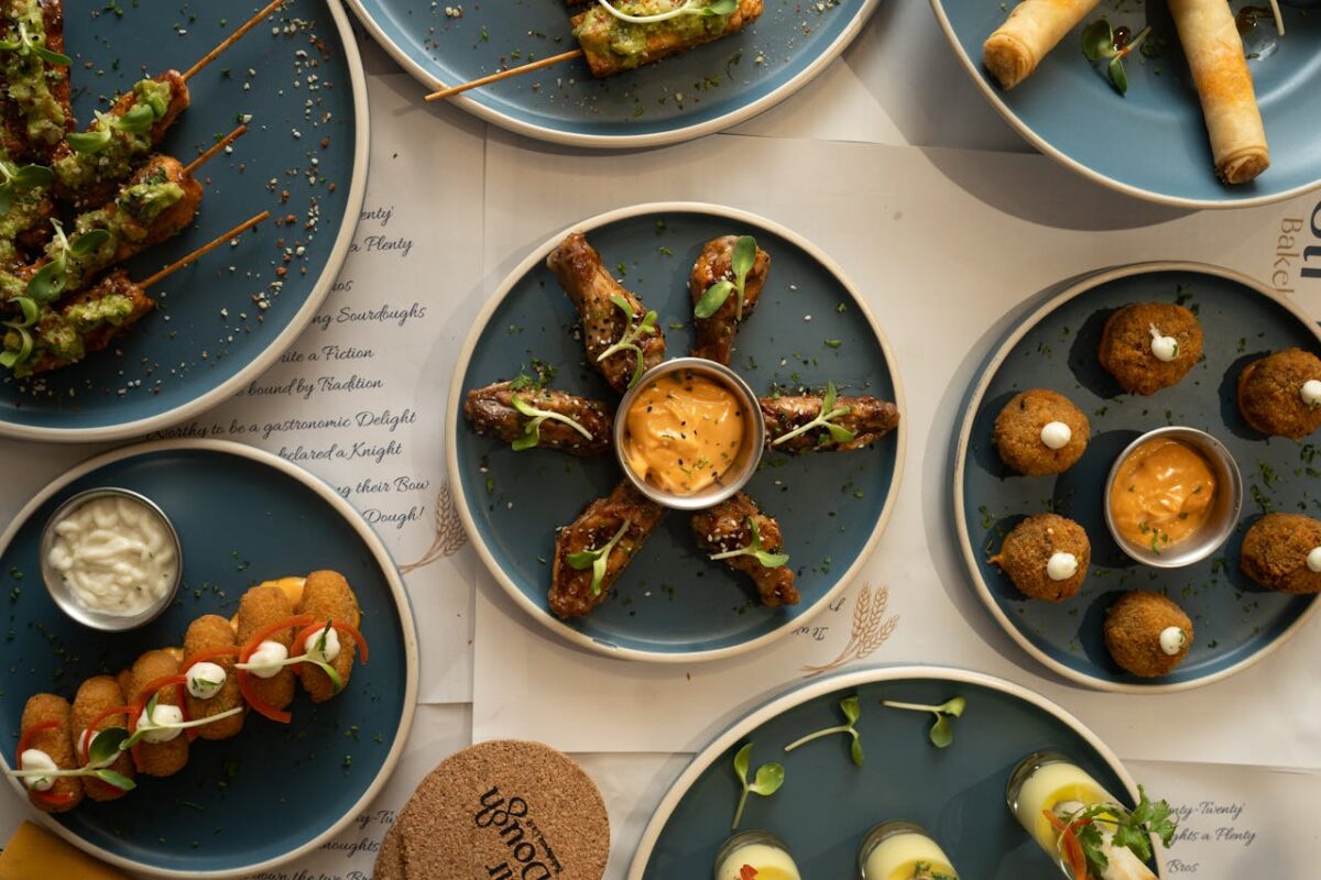 A top view of various appetizers artistically arranged on blue plates with dipping sauces.